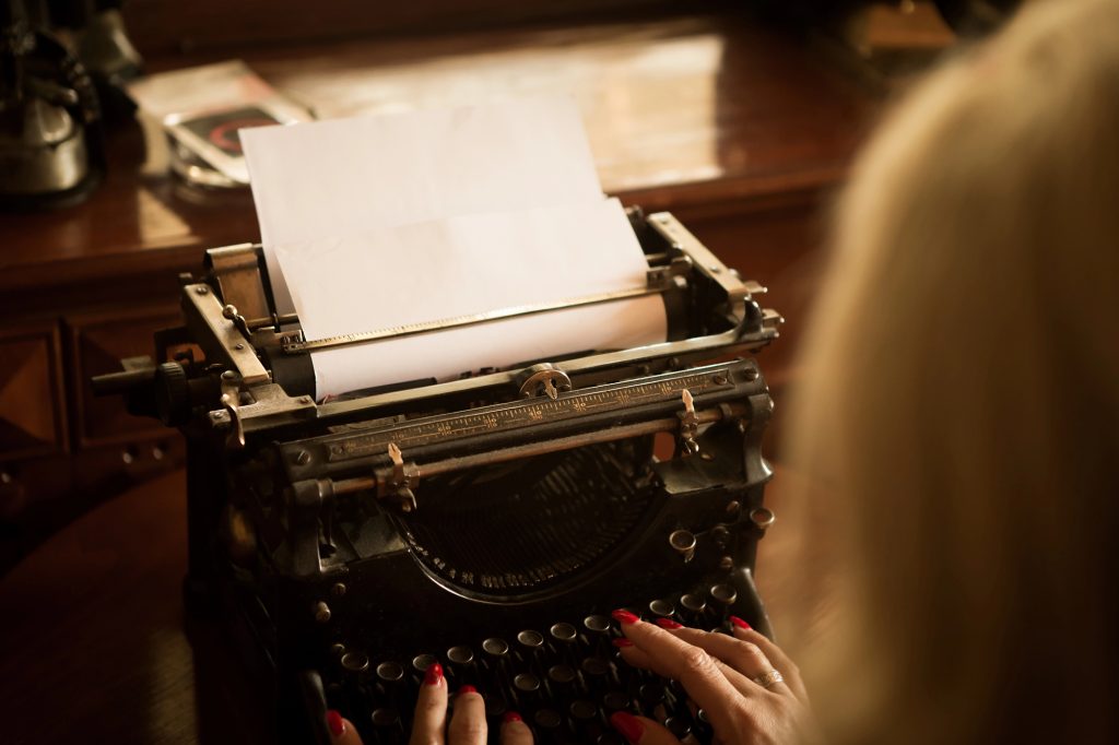A woman looking at the paper on the old typewriter.
